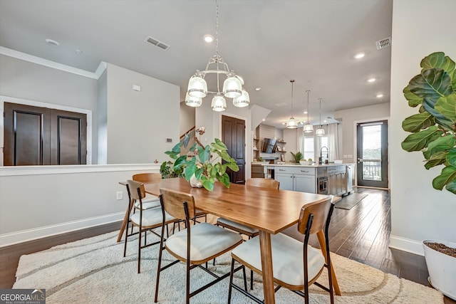 dining area with dark wood-type flooring, sink, and an inviting chandelier