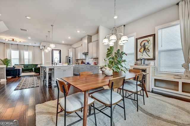 dining room with a notable chandelier, sink, and dark hardwood / wood-style flooring