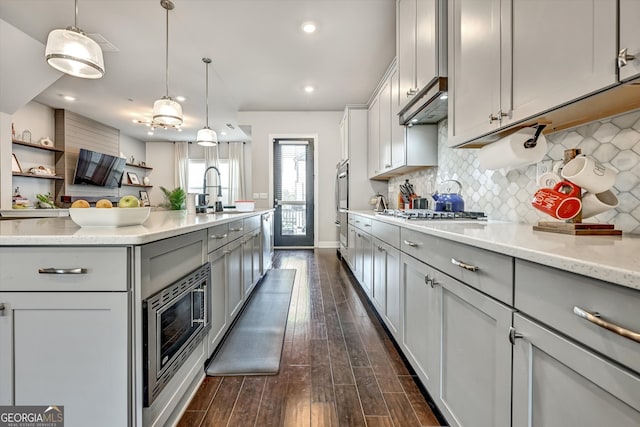 kitchen featuring gray cabinetry, decorative light fixtures, sink, light stone counters, and dark hardwood / wood-style floors