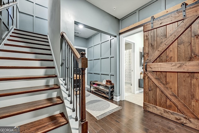 stairway with a barn door and wood-type flooring