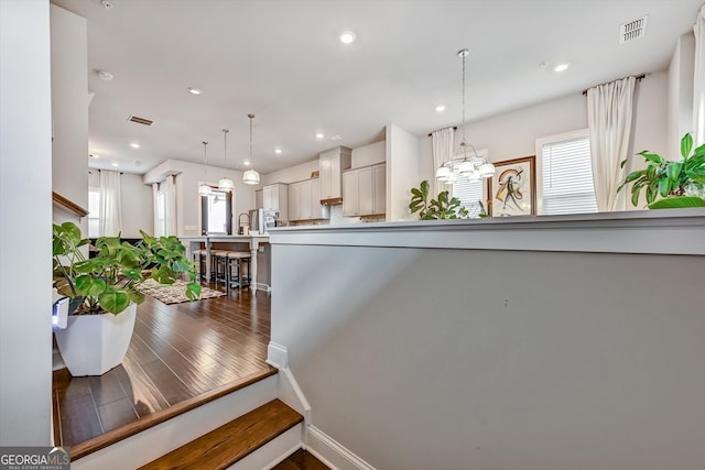 interior space featuring dark wood-type flooring, hanging light fixtures, and white cabinetry