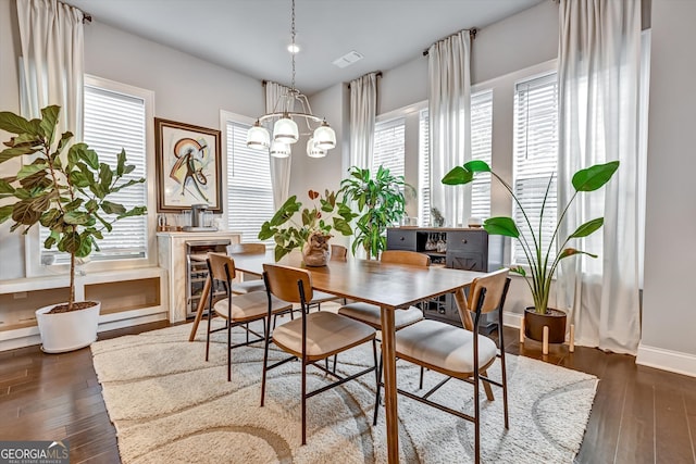 dining area featuring an inviting chandelier, dark hardwood / wood-style floors, and beverage cooler