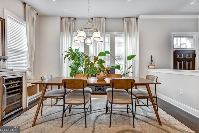 dining area with an inviting chandelier, beverage cooler, hardwood / wood-style flooring, and a wealth of natural light