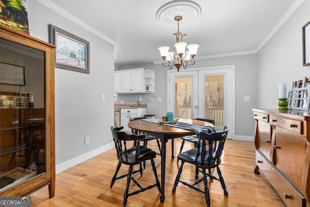 dining area with an inviting chandelier, french doors, ornamental molding, and light hardwood / wood-style flooring