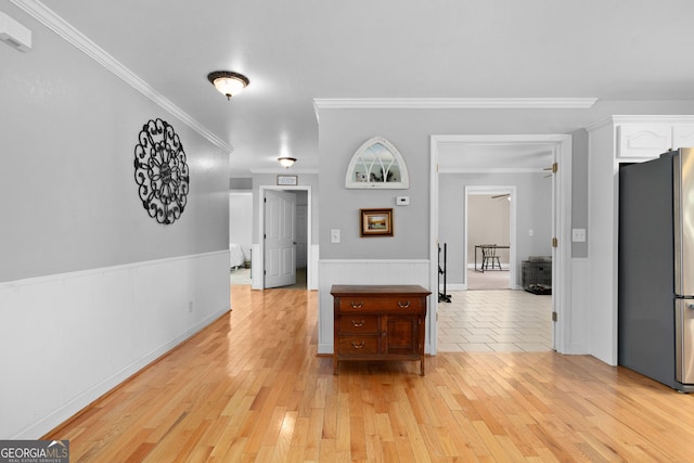 corridor with ornamental molding and light wood-type flooring