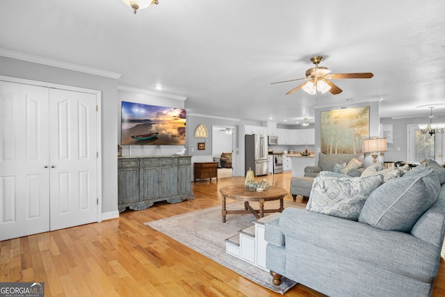 living room with ceiling fan with notable chandelier, ornamental molding, and light hardwood / wood-style floors