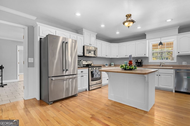 kitchen with white cabinets, appliances with stainless steel finishes, and light wood-type flooring