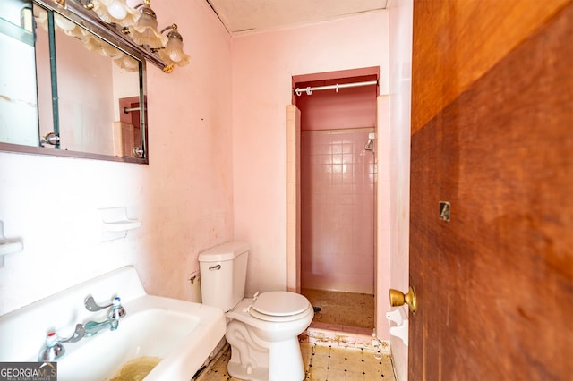 bathroom featuring a tile shower, toilet, and sink