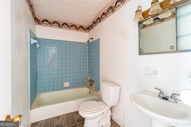 full bathroom featuring tiled shower / bath combo, sink, a textured ceiling, and toilet