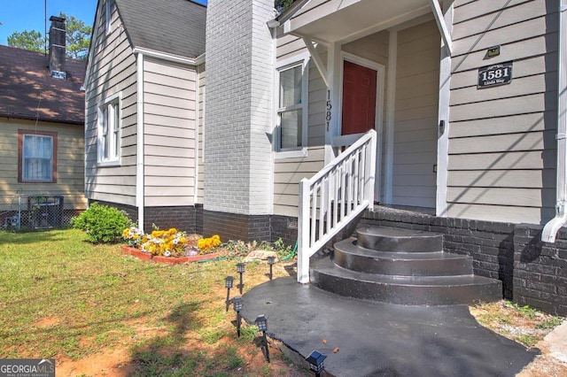 view of exterior entry with a yard and central AC unit