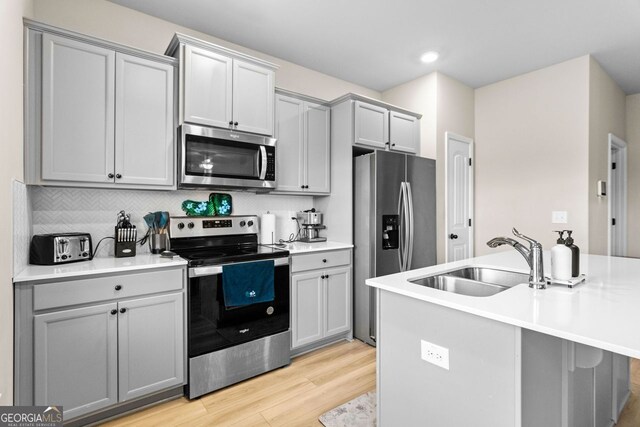 kitchen featuring gray cabinetry, sink, light wood-type flooring, and stainless steel appliances