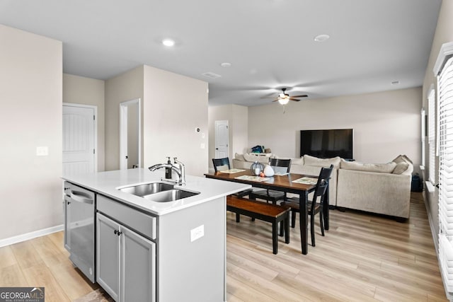 kitchen featuring sink, an island with sink, stainless steel dishwasher, and light hardwood / wood-style flooring