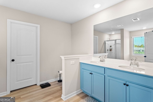 bathroom featuring hardwood / wood-style flooring, vanity, and a shower with shower door