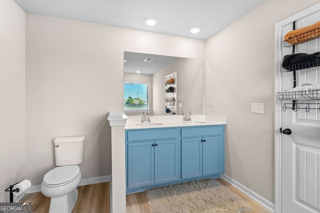 bathroom with toilet, vanity, and hardwood / wood-style flooring