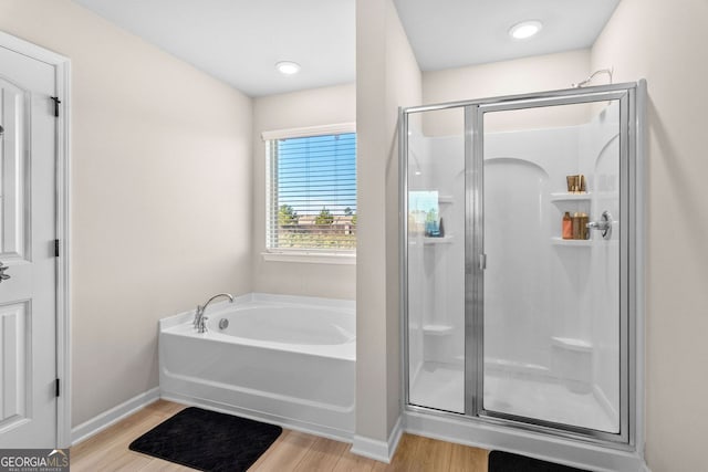 bathroom featuring plus walk in shower and hardwood / wood-style flooring