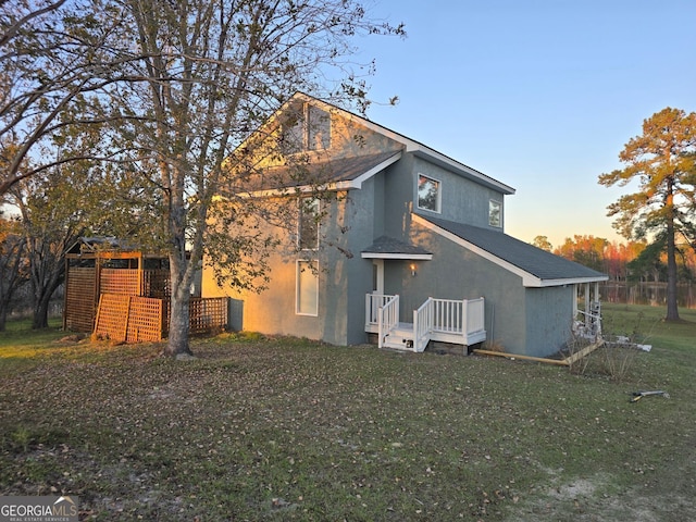 back house at dusk featuring a yard