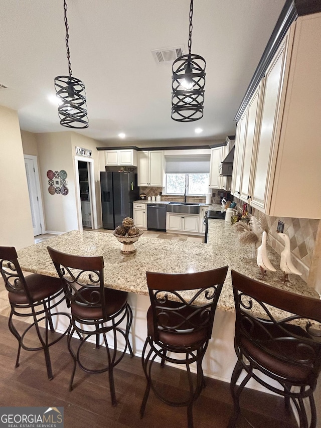 kitchen with dishwashing machine, pendant lighting, decorative backsplash, sink, and black fridge with ice dispenser