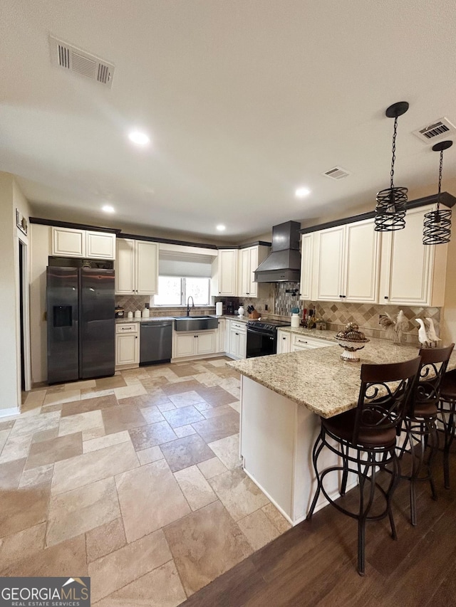 kitchen with black appliances, custom range hood, sink, decorative light fixtures, and kitchen peninsula