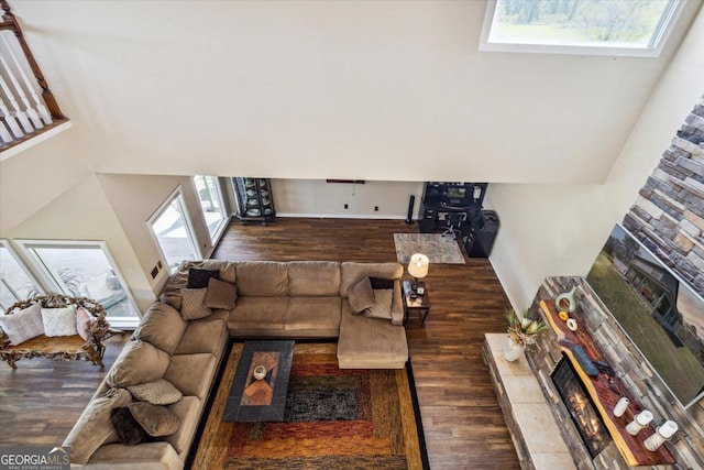 living room with dark wood-type flooring and a stone fireplace