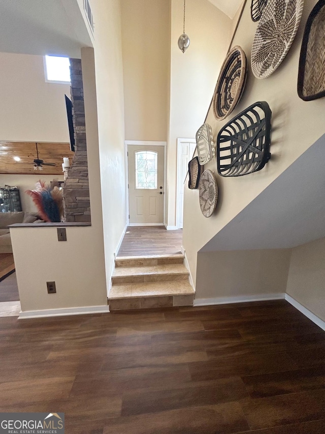 foyer with ceiling fan, a high ceiling, and dark wood-type flooring