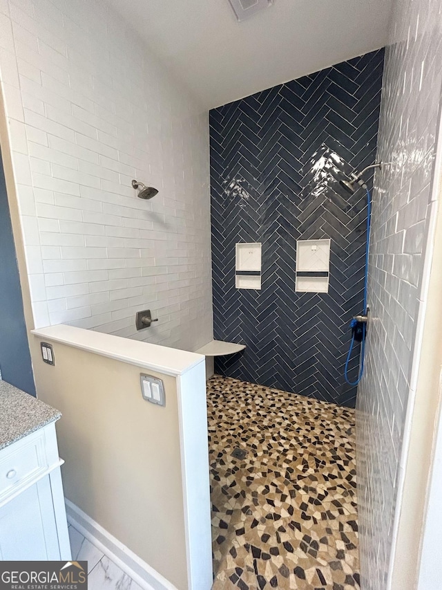 bathroom with tiled shower and vanity