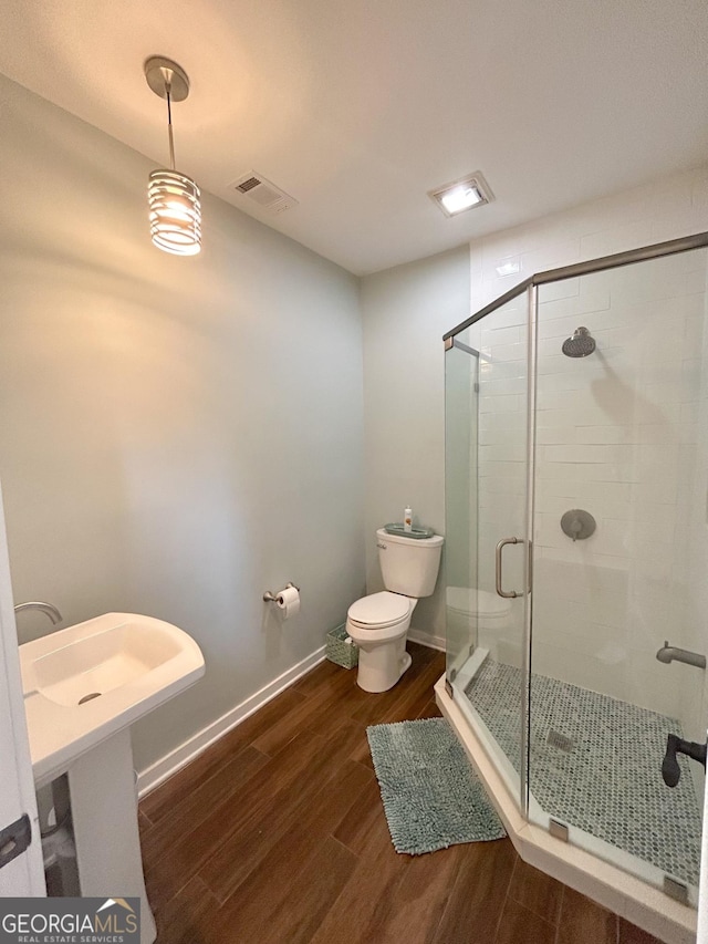 bathroom with hardwood / wood-style floors, toilet, and walk in shower