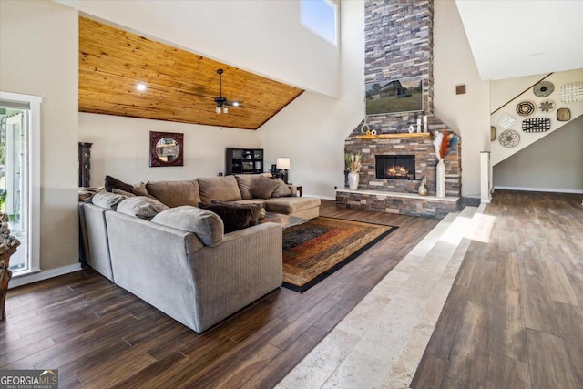 living room featuring ceiling fan, dark hardwood / wood-style floors, high vaulted ceiling, and a stone fireplace