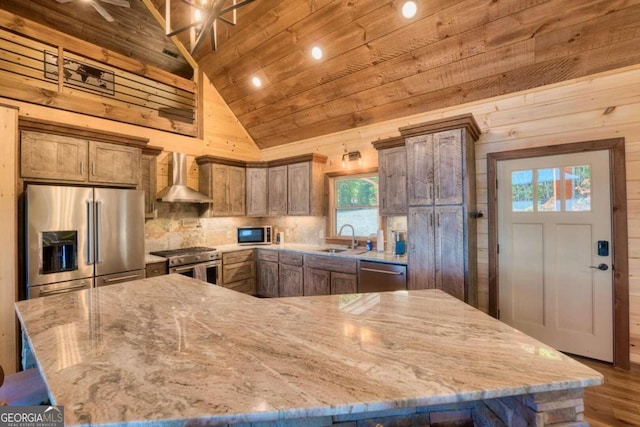 kitchen with wall chimney range hood, hardwood / wood-style flooring, stainless steel appliances, and plenty of natural light