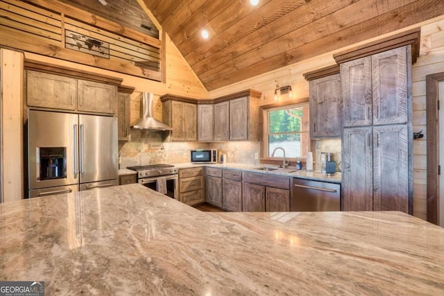 kitchen featuring light stone countertops, vaulted ceiling, sink, wall chimney exhaust hood, and stainless steel appliances