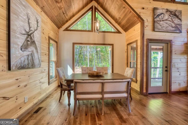 dining space featuring wood walls, a healthy amount of sunlight, and wood-type flooring