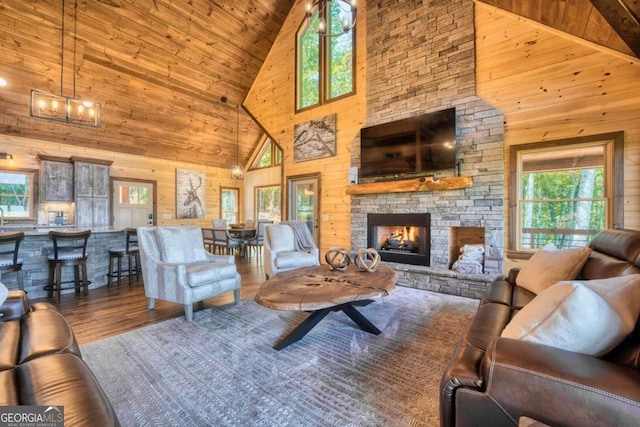 living room featuring a stone fireplace, high vaulted ceiling, and a wealth of natural light