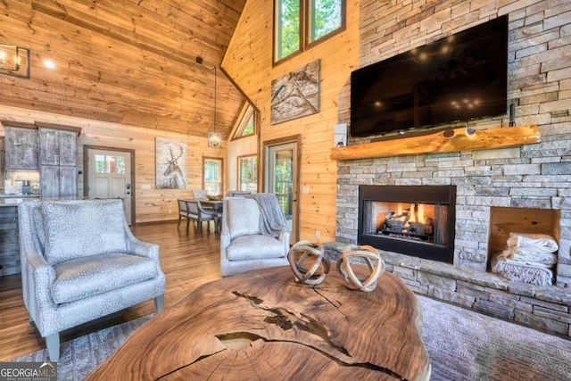 living room featuring a stone fireplace, wooden walls, high vaulted ceiling, and a wealth of natural light