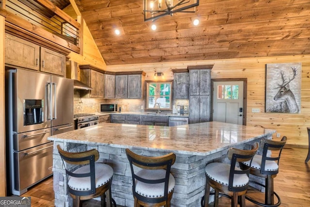 kitchen featuring high quality appliances, a large island, wooden ceiling, light stone counters, and hardwood / wood-style flooring