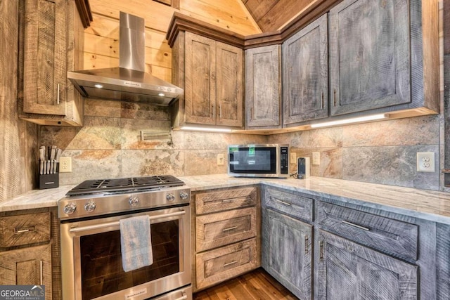 kitchen with tasteful backsplash, light stone countertops, wall chimney range hood, stainless steel appliances, and dark wood-type flooring