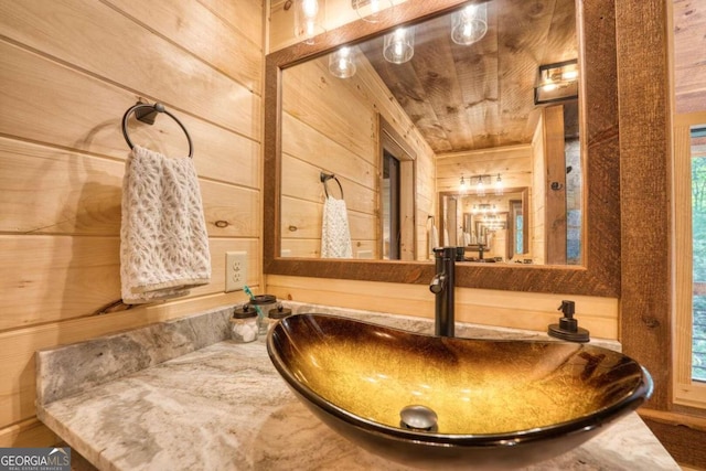 bathroom with a wealth of natural light, vanity, and wooden walls