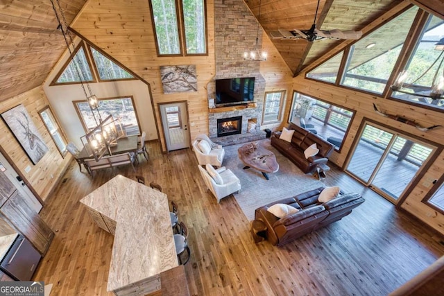 living room with high vaulted ceiling, a wealth of natural light, and a stone fireplace