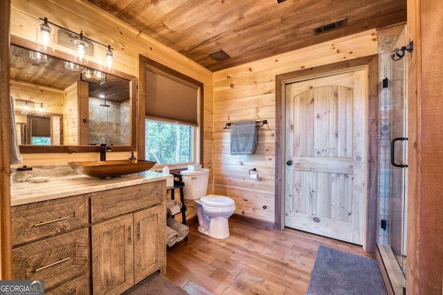 bathroom featuring wood walls, hardwood / wood-style floors, toilet, walk in shower, and vanity