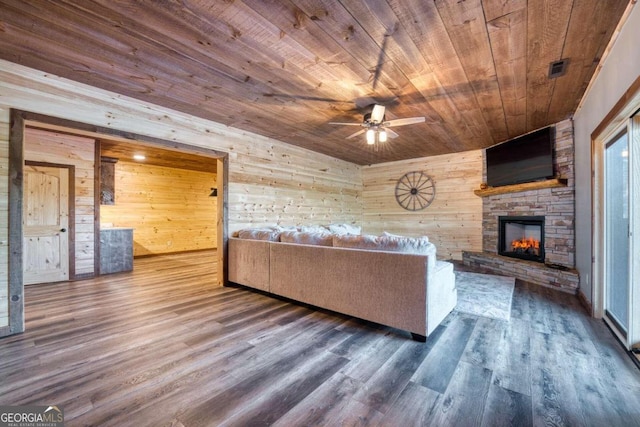 unfurnished living room featuring wood walls, a stone fireplace, wood ceiling, wood-type flooring, and ceiling fan