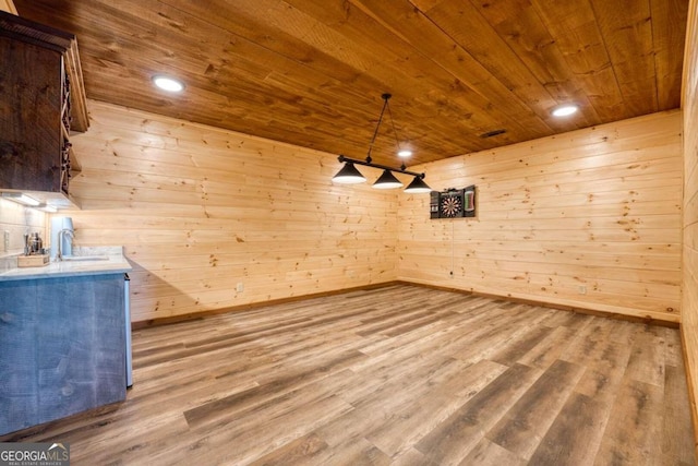 interior space featuring wooden walls, hanging light fixtures, wooden ceiling, hardwood / wood-style floors, and dark brown cabinetry