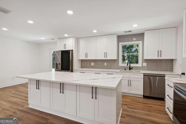 kitchen with white cabinets, stainless steel appliances, a center island, and sink