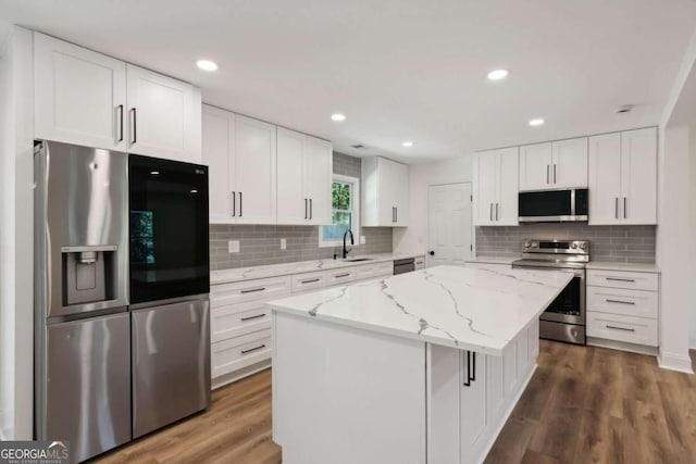 kitchen featuring sink, white cabinets, a center island, light stone countertops, and appliances with stainless steel finishes