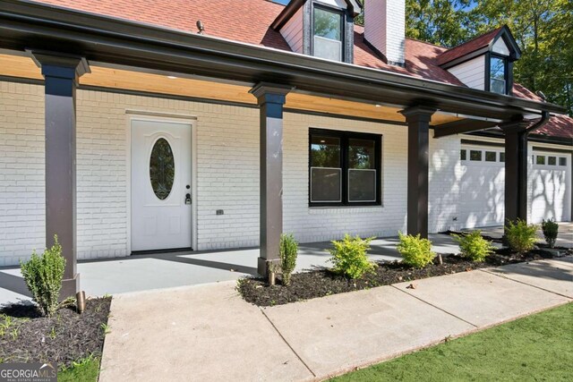 doorway to property with a garage and a porch