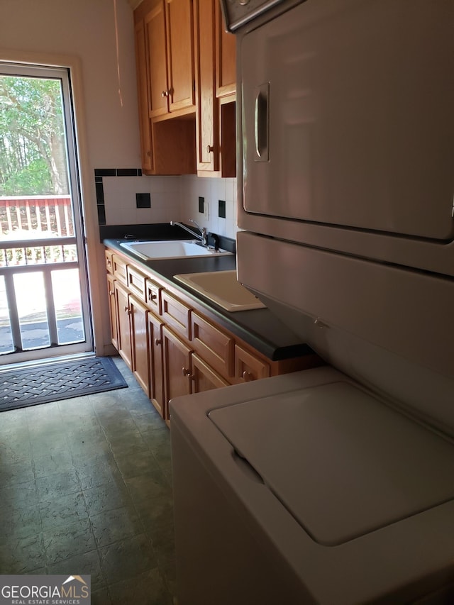 kitchen with backsplash, sink, and stacked washing maching and dryer