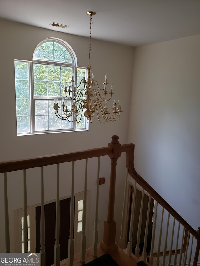 stairway with a notable chandelier