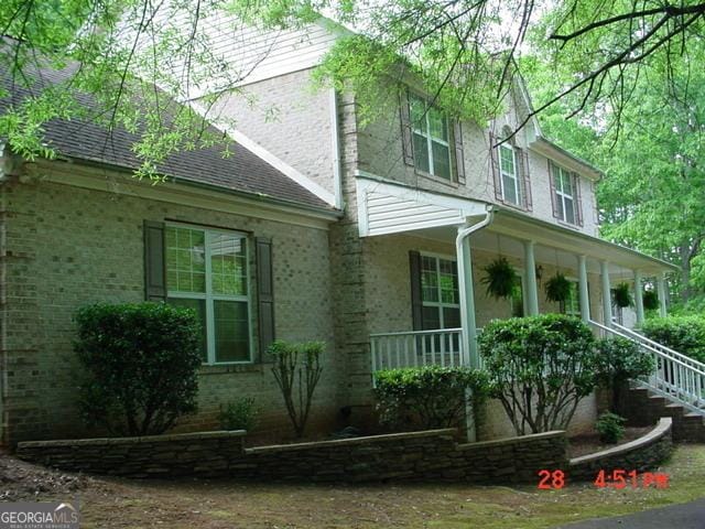 87 Mcmichael Way, Hoschton, GA 30548 - view of side of property with brick siding, covered porch, stairway, and roof with shingles