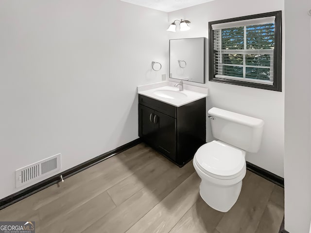 bathroom with wood-type flooring, vanity, and toilet