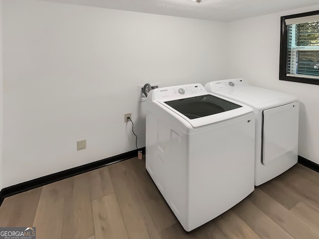 clothes washing area with hardwood / wood-style flooring and washing machine and clothes dryer