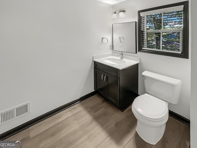 bathroom with hardwood / wood-style floors, vanity, and toilet