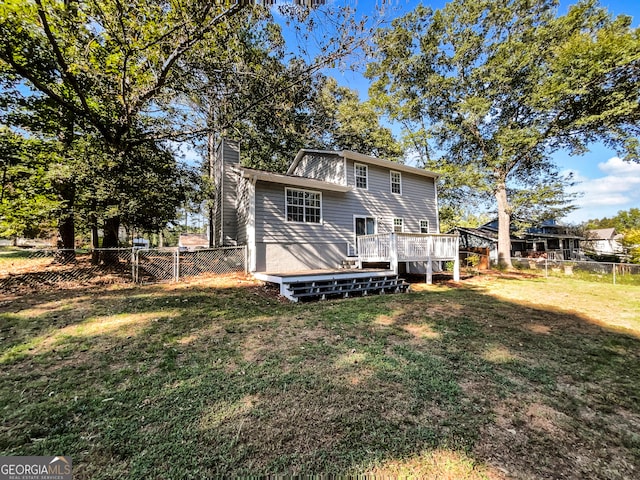 rear view of house with a wooden deck and a yard