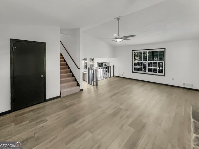 unfurnished living room with ceiling fan, light wood-type flooring, and lofted ceiling